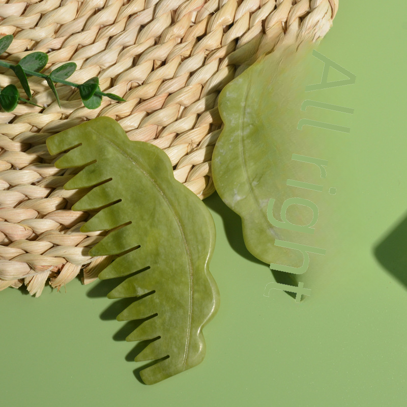Green scalloped scalp massage combs on a green surface beside woven straw.