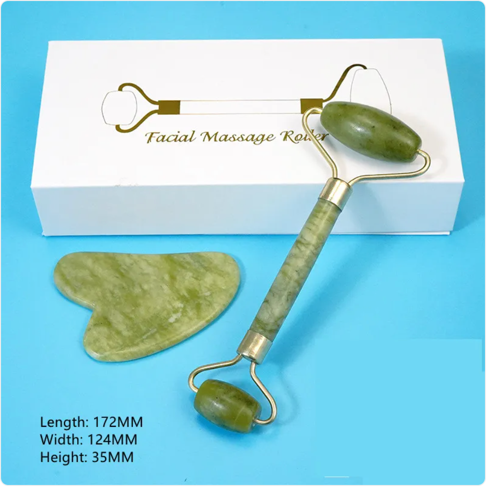 Green facial roller and gua sha tool arranged beside a white box on blue.