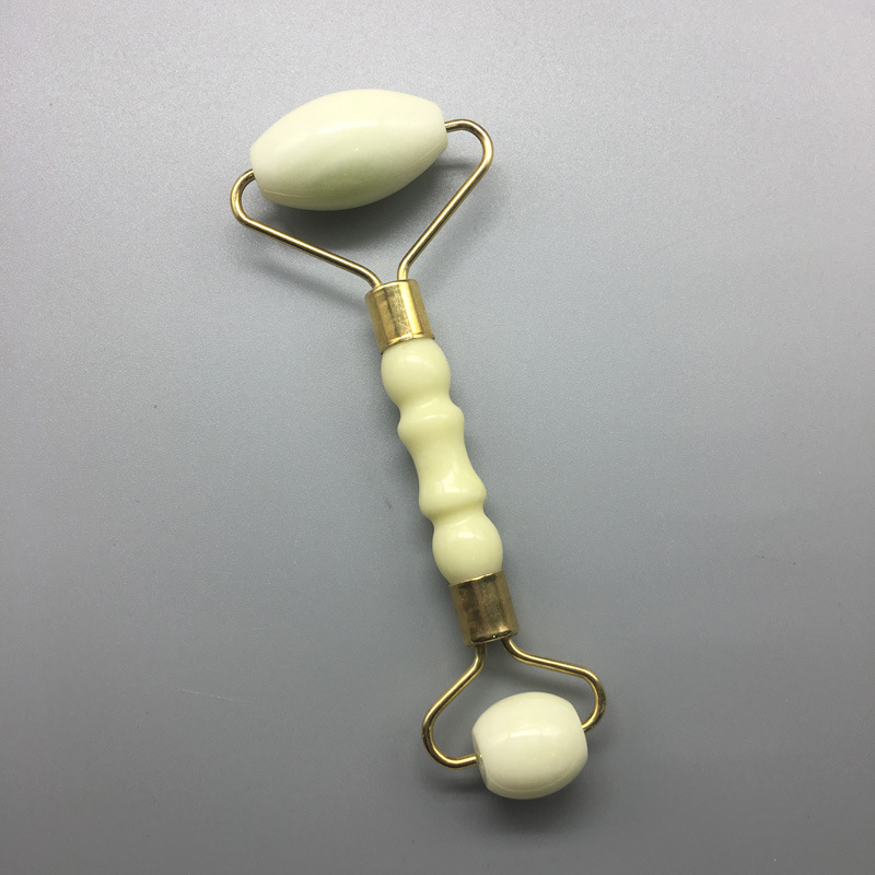 White double-ended facial roller with a shaped handle and gold-colored frame.
